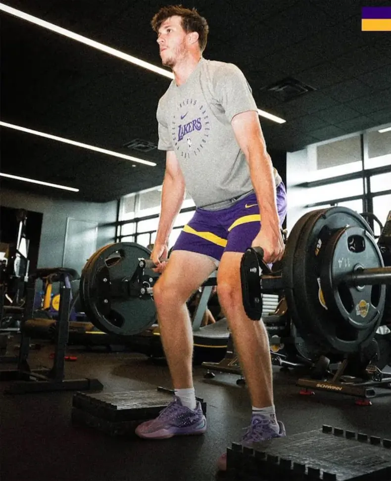 Athlete in a Lakers shirt lifting weights in the gym, performing a deadlift exercise for strength training.